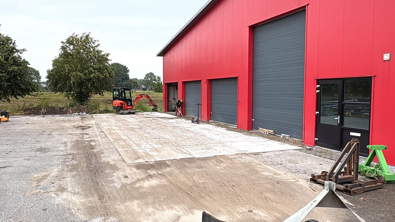 Gebezemde betonplaten aangebracht bij een bedrijfspand voor een sterke en slipvaste terreinverharding.